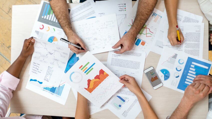 Unrecognizable group of business people in a meeting at the office looking at strategy documents.