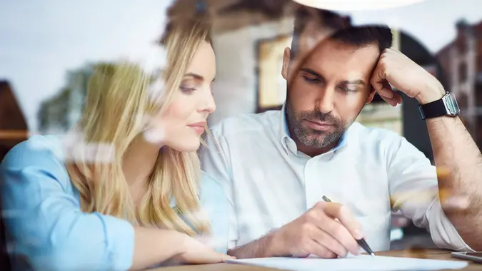 couple in window looking at paper