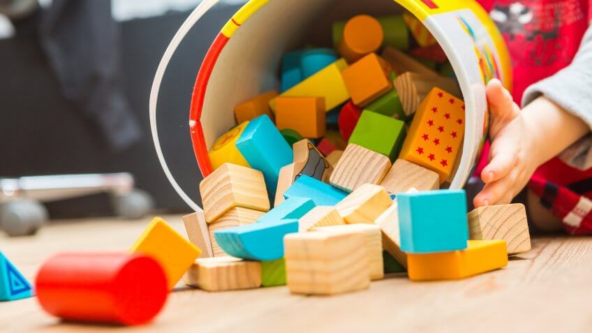 Small boy playing with wooden blocks on floor.