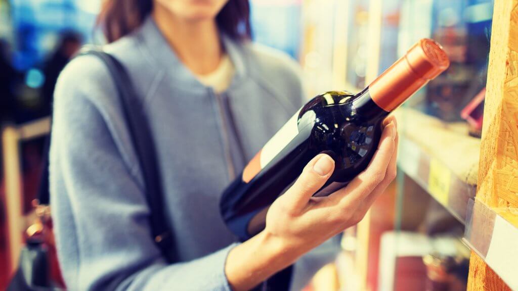 Alcohol woman examining a bottle of wine