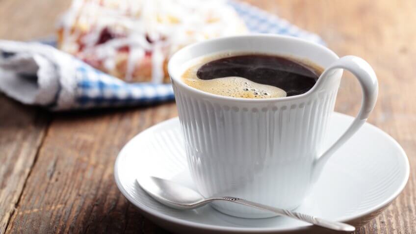 steaming black coffee in front of breakfast pastry