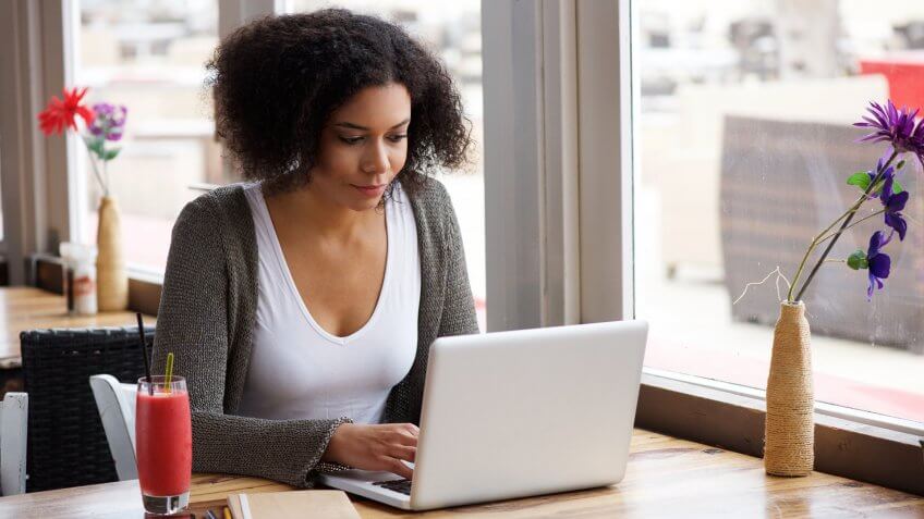 woman on laptop at cafe next to window