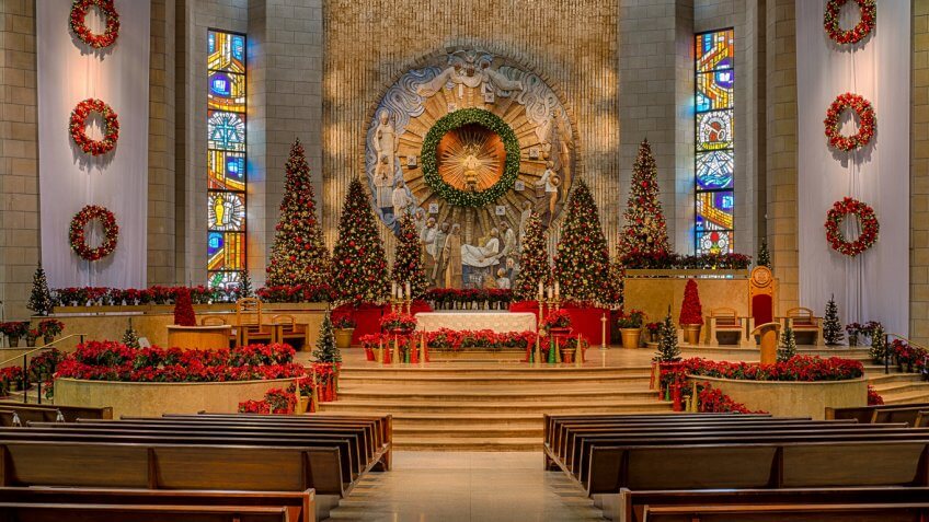church decorated with christmas trees, wreaths and flowers