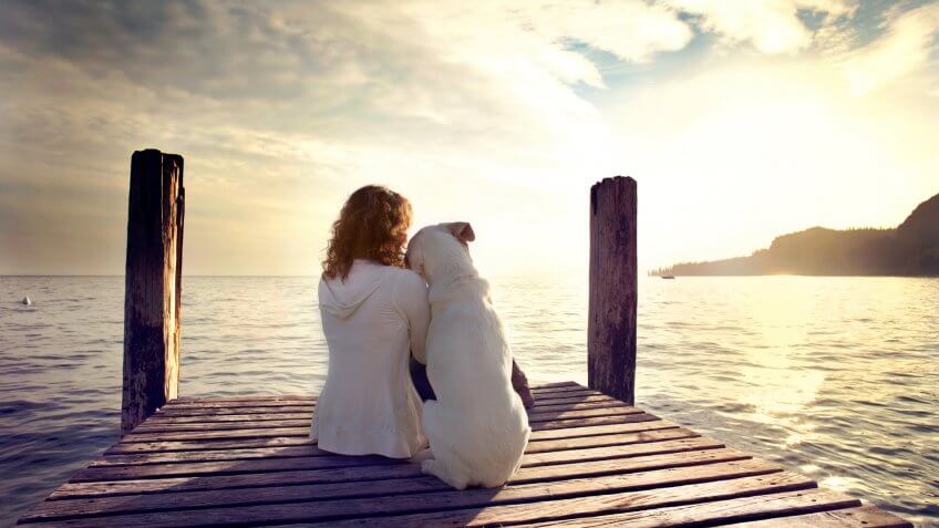 woman embracing sweetly his dog while looking the view.