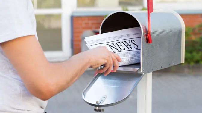 Close-up of Person Hands Opening His Mailbox To Remove Newspaper.