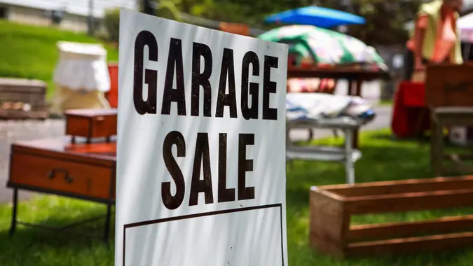 Garage sale sign on the shady lawn of a suburban home, shallow focus in center of sign.