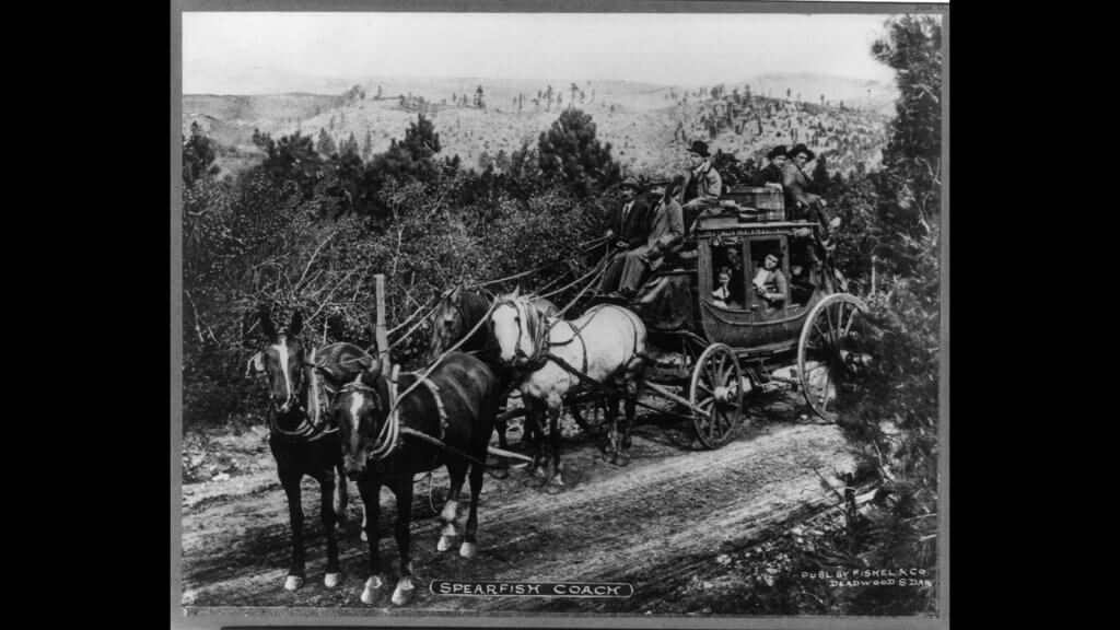 Photograph shows Spearfish stagecoach on dirt road with driver and passengers circa 1900 to 1910 Photograph shows Spearfish stagecoach on dirt road with driver and passengers circa 1900 to 1910