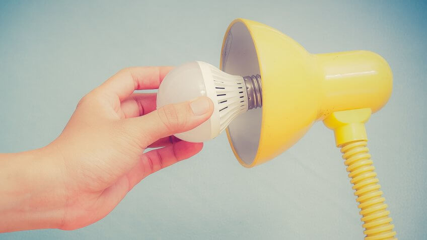 person putting an LED light bulb into a lamp