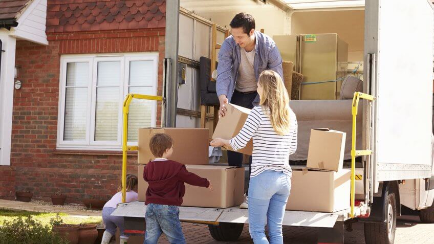 family lifting moving boxes into truck
