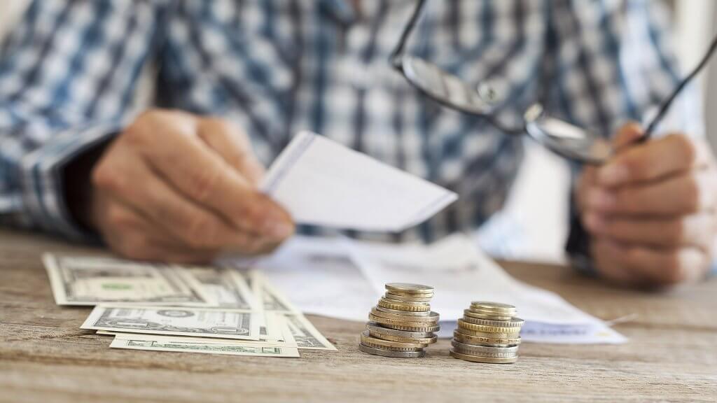 Start Paying Yourself First close up of cash and coins in front of a man