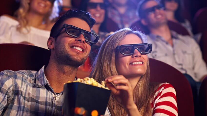 Couple sharing popcorn watching a 3D movie at the cinema theatre Theater
