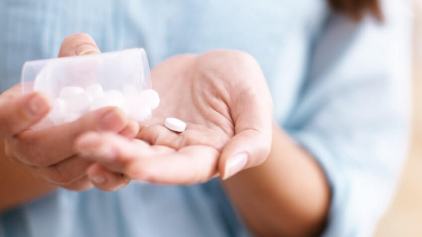 woman dumping aspirin into her hand from a pill bottle