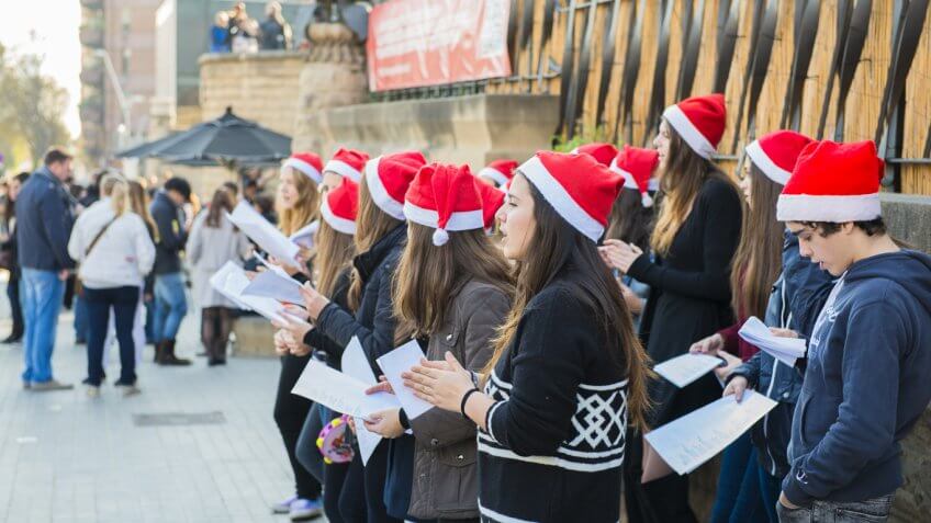 teen christmas choir singing on a busy sidewalk