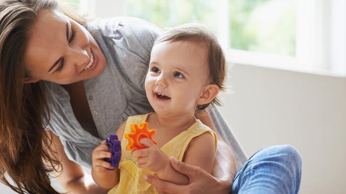 Shot of a cute baby girl sitting on the floor with her mom and playing with toys.