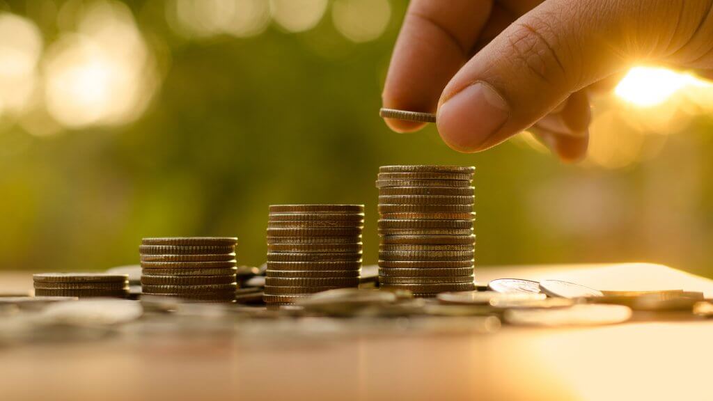 Bank on a Larger Maximum Possible Benefit person stacking coins in different columns