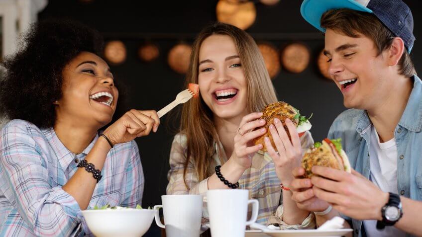 Group of young friends eating burgers and a salad
