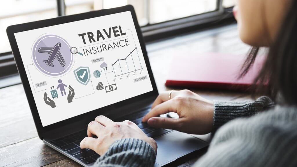 Travel Insurance woman researching travel insurance on computer