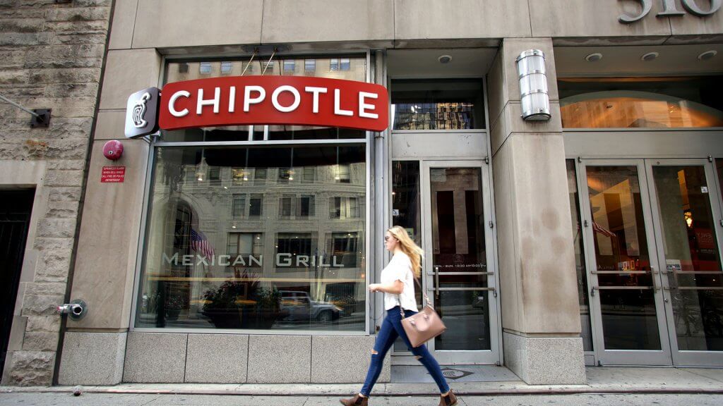 Another Chipotle Norovirus Outbreak woman walking past a chipotle restaurant