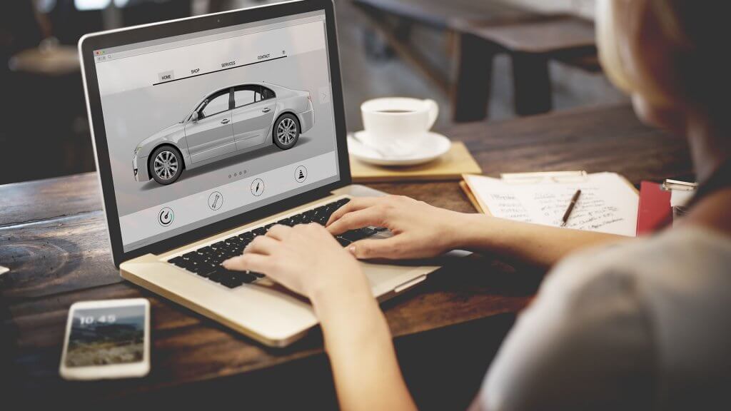 Month 6 Decide on Your Car woman researching new cars on laptop
