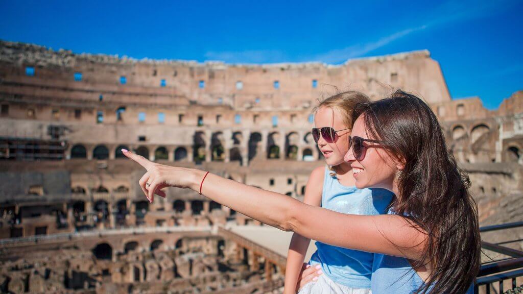 Include Access to the Finer Things mom carrying daughter and pointing at something at the Colosseum in Rome