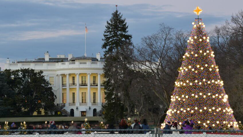 front street view of the white house with people taking pictures of the giant christmas tree near the perimeter