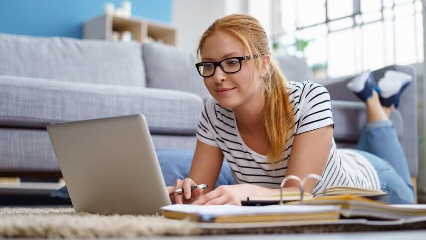 young woman studying on the floor with laptop