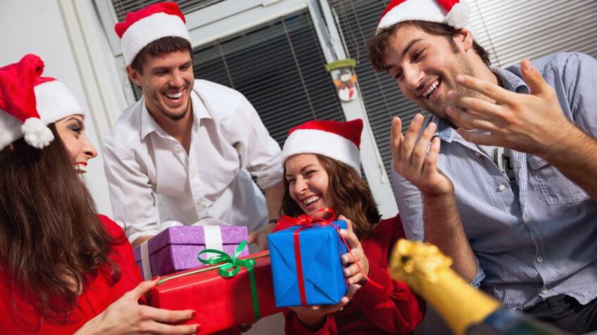 friends laughing and passing out christmas gifts