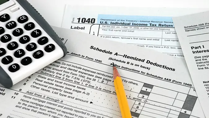 U.S. tax forms, Schedule A for itemized deductions, calculator and pencil, representing tax filing and deduction planning.
