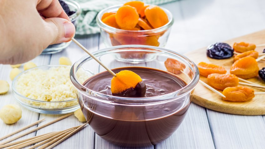 Making apricot and prunes lollipops, covered with chocolate and macadamia nuts.
