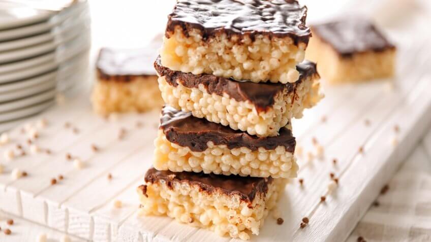 Delicious rice crispy treats with chocolate on wooden board.