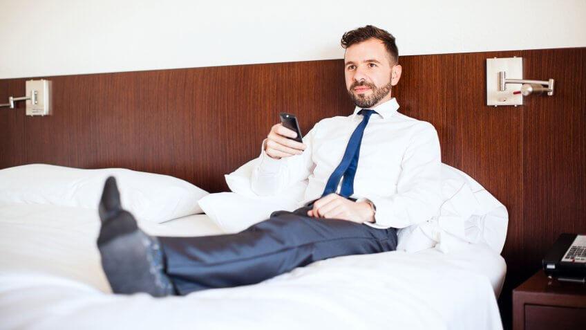 man in suit laying on bed at hotel