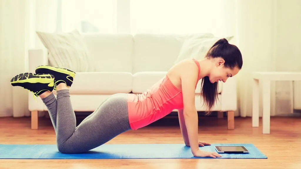 woman in pushup or yoga position and looking at tablet