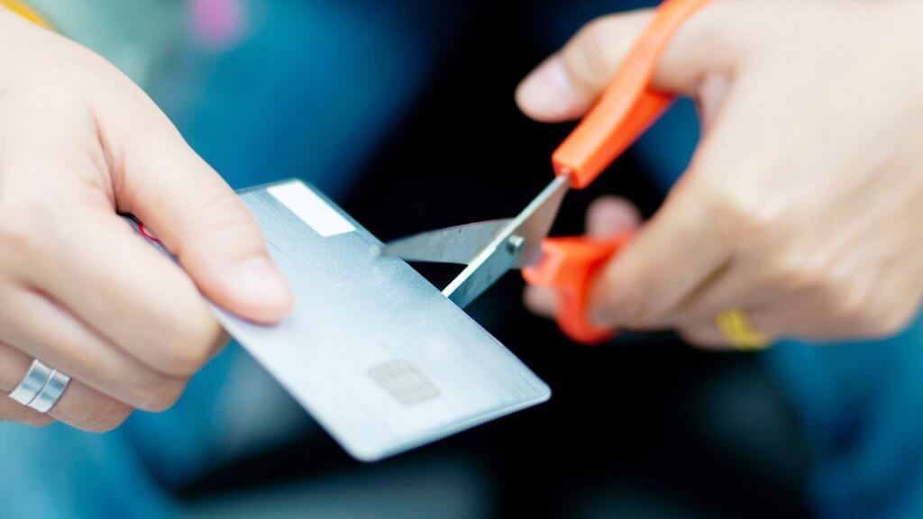 Cut Up Credit Cards That Fueled Overspending close up of hands cutting credit card