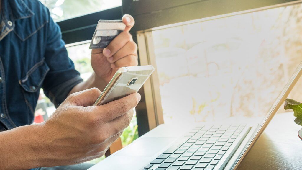 Make Double Payments on Credit Cards hand holding credit card and phone