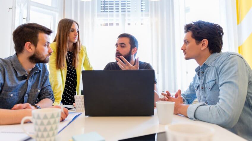 group of people sitting around a laptop