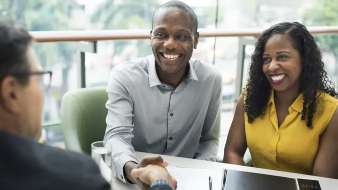 smiling woman and man shaking hands with a financial adviser