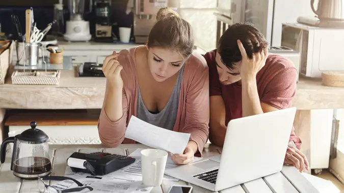 man and woman looking at document in front of laptop in the kitchen