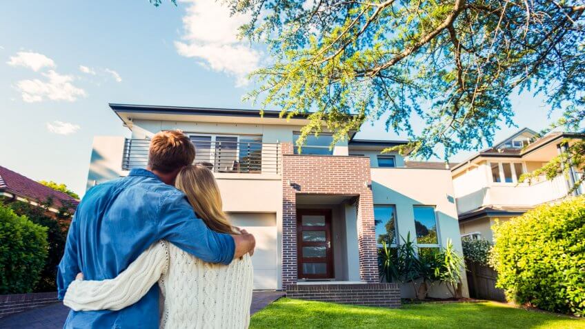 Couple standing in front of their new home.
