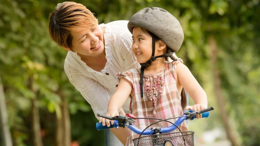 Vintage of little Asian child with mother practice to riding a bicycle.