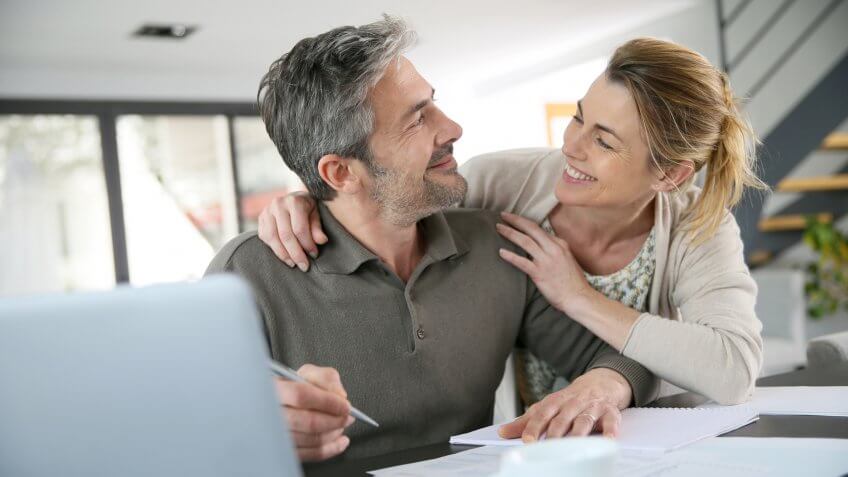 Couple calculating financial savings on internet.
