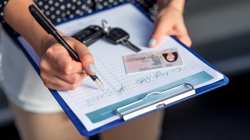 Young woman car rental inspector filling contract.
