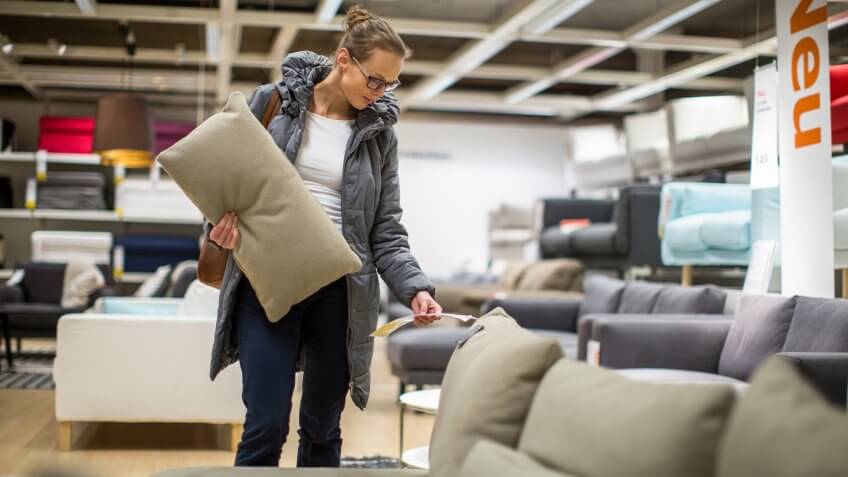 Pretty, young woman choosing the right furniture for her apartment in a modern home furnishings store