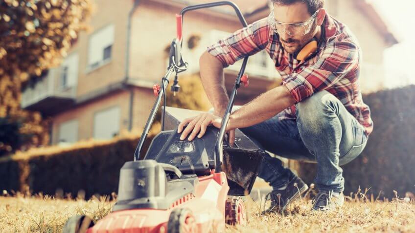 Man cutting grass in his yard with lawn mower.