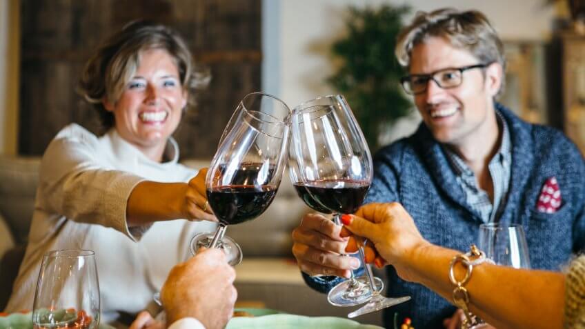 People cheering at celebration table with wine glasses and smiles on their faces.
