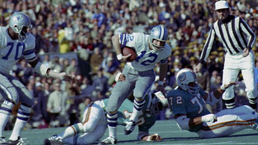 Roger Staubach; Jim Riley Dallas Cowboys quarterback Roger Staubach (12) tries to escape the grasp of Miami Dolphins defender Jim Riley (70) during action of Super Bowl VI in New Orleans, La.