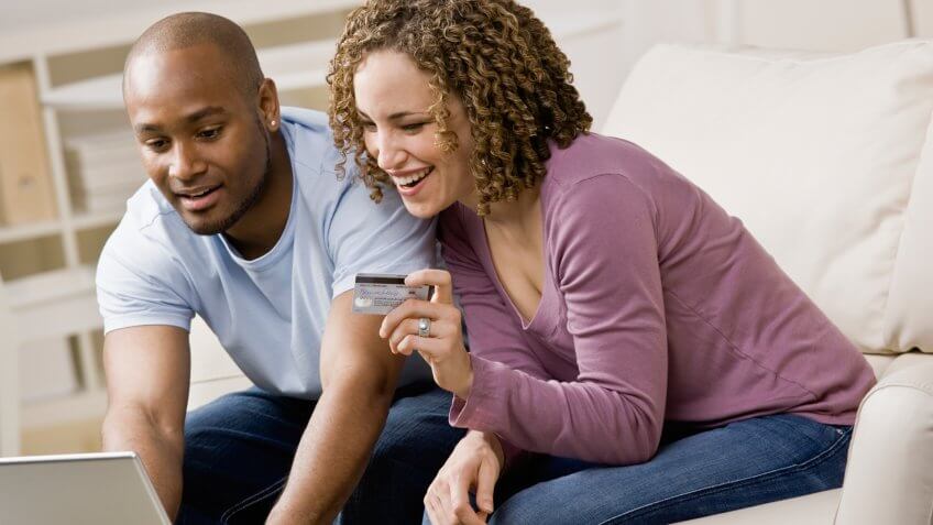 Happy couple using credit card to shop online conveniently.