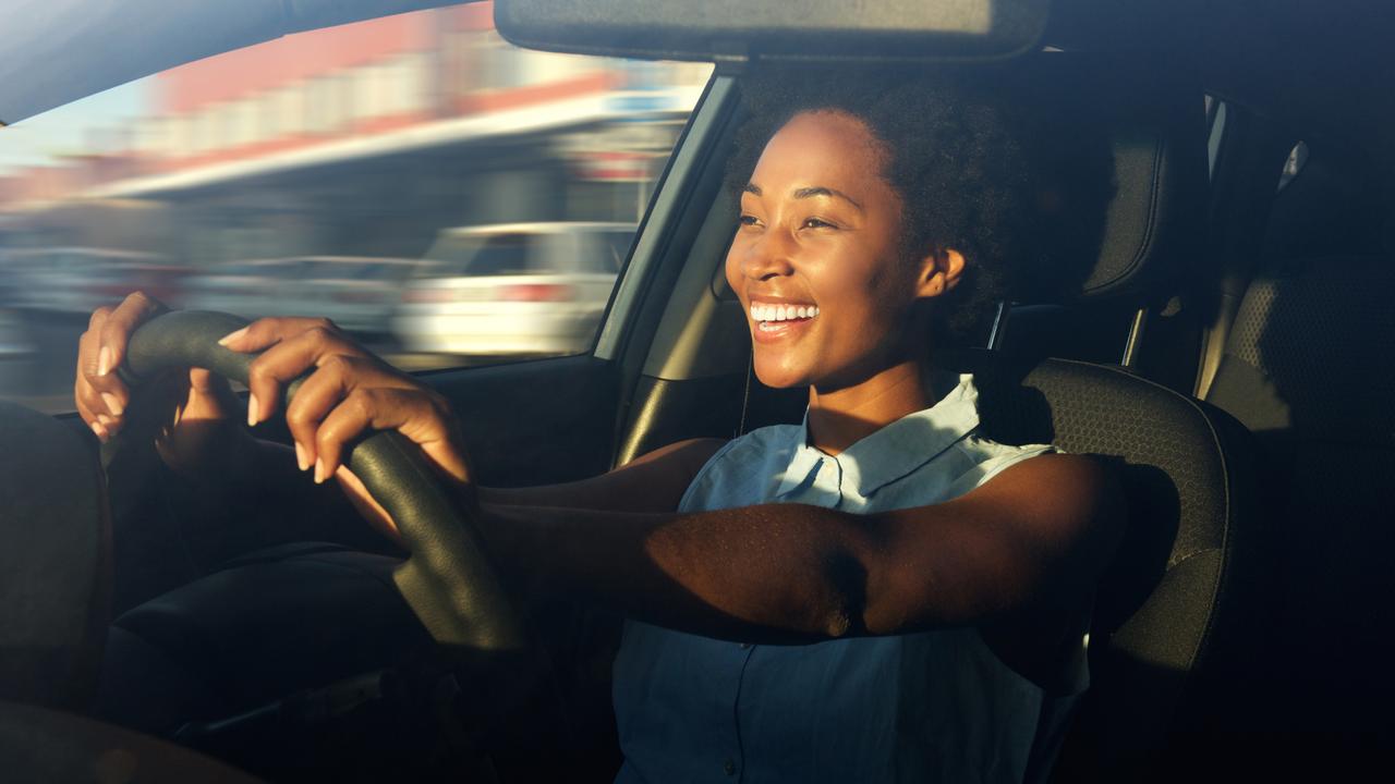 Portrait of smiling young african american woman driving a car.