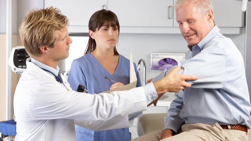 doctor examining elderly man's arms