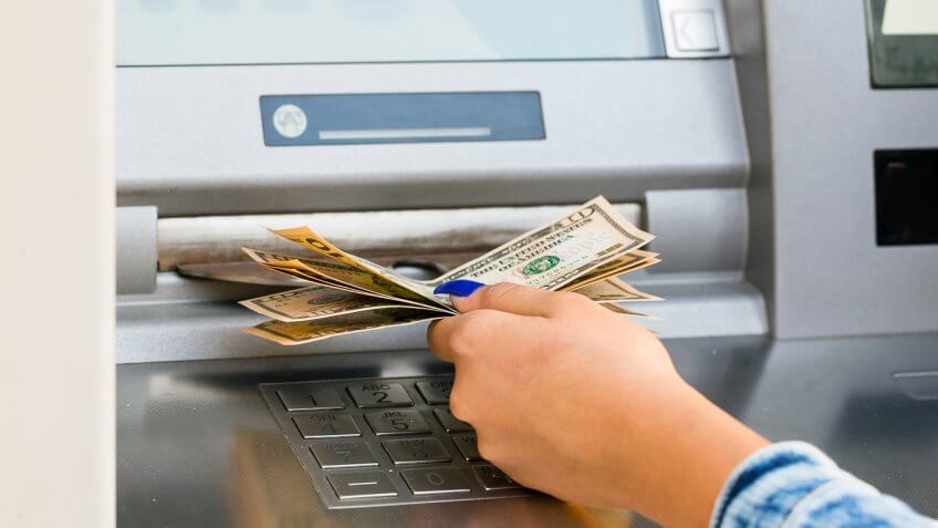 woman pulling $10 out of an ATM