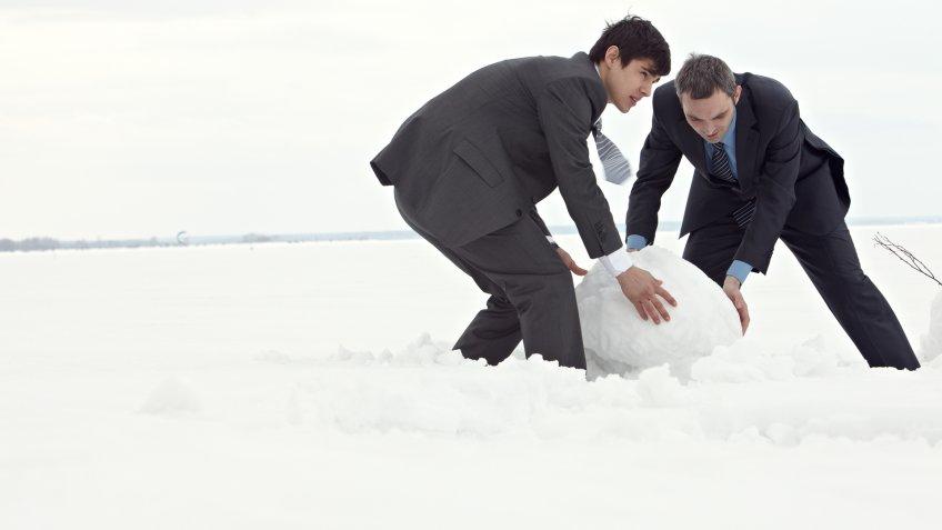 two men rolling a giant snowball